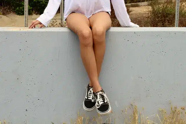 Kvinna som sitter på betong och visar ben